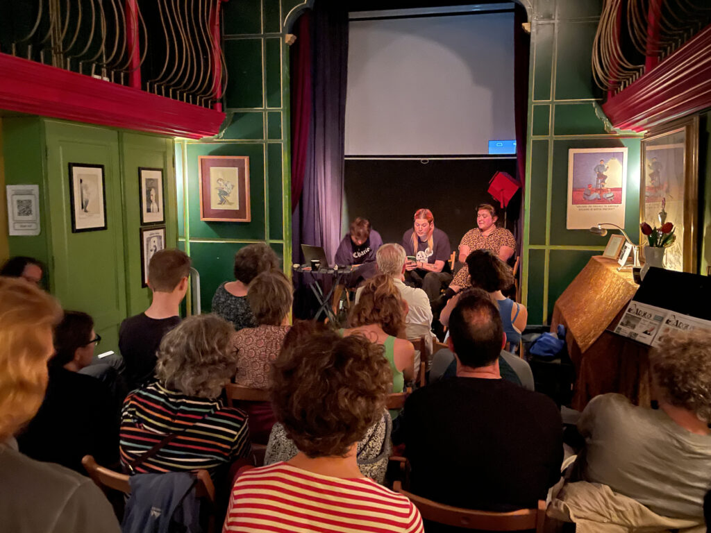 foto van het Torpedotheater na de vertoning van een aflevering van Julio Torres met de sprekers op het podium en het publiek op de rug gezien.