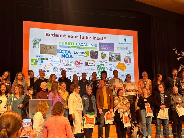 De coördinatoren van alle projecten in Nederland van Herstel Dichtbij worden op het podium in het zonnetje gezet.